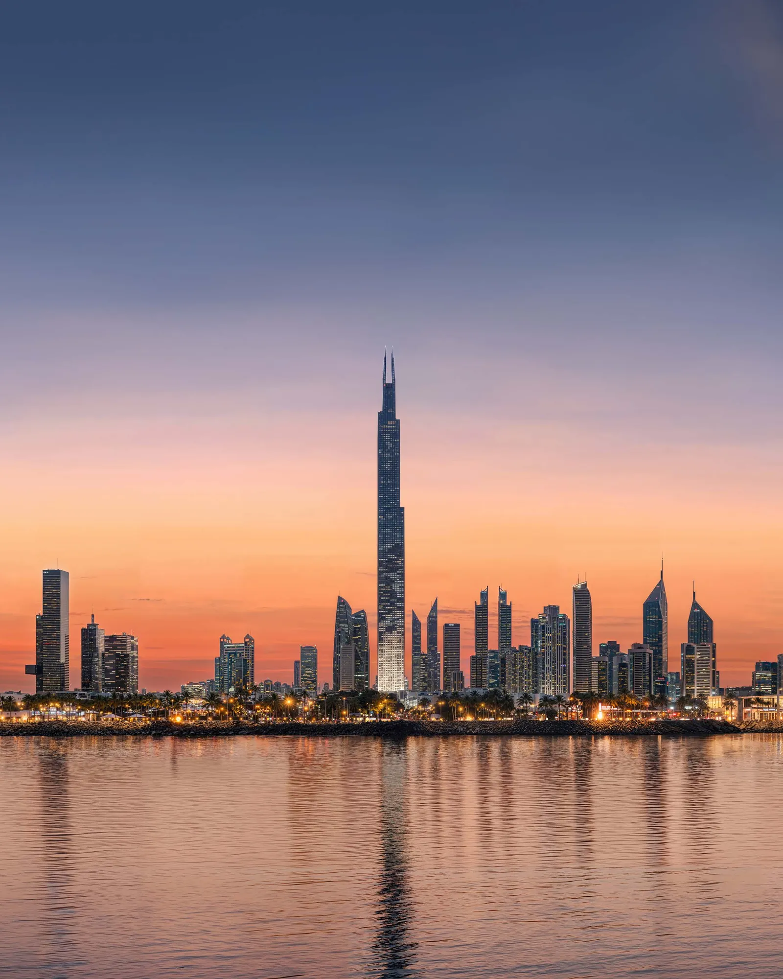 Burj Azizi over Dubai's skyline at sunset, reflected in the water